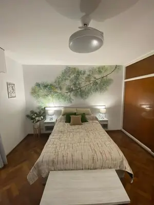 a bedroom with a bed with a tree mural on the wall at Departamento Centro Córdoba con Cochera Privada in Cordoba