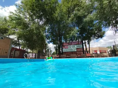 a large swimming pool with a sign in the background at Cabañas Torres in Mina Clavero