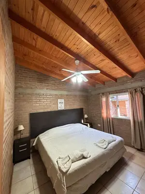 a bedroom with a large bed with a ceiling fan at Cabañas Torres in Mina Clavero