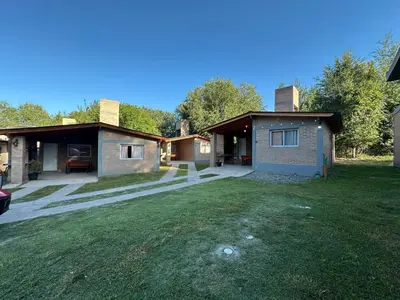 a house with a grass yard in front of it at Cabañas Torres in Mina Clavero