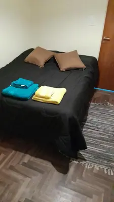 a bed with a black comforter and pillows on it at Departamento en Carlos Paz, céntrico in Villa Carlos Paz