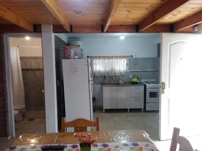 a kitchen with a white refrigerator and a table at Cabañas Jazmines del Lago in San Roque