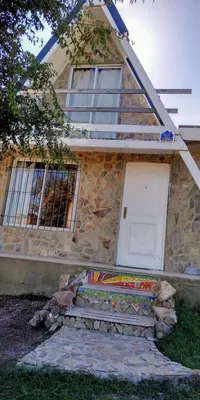 a stone house with a white door and windows at Cabañas Jazmines del Lago in San Roque