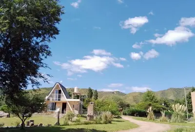 a house in a field with mountains in the background at Cabañas Jazmines del Lago in San Roque