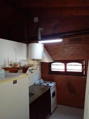 a small kitchen with a stove and a window at Complejo Don Emilio in Los Reartes