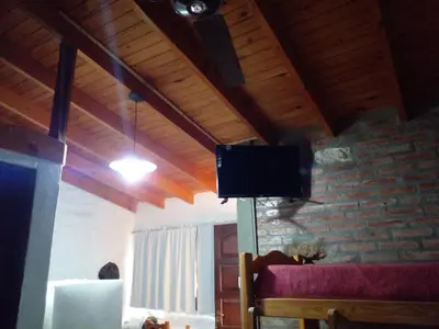 a living room with a tv on a brick wall at Complejo Don Emilio in Los Reartes