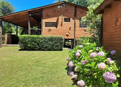 a building with a bunch of flowers in the yard at Complejo Don Emilio in Los Reartes