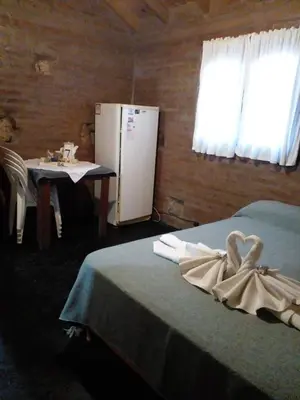 a room with a bed and a table and a refrigerator at Complejo Don Emilio in Los Reartes