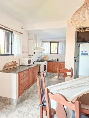 a kitchen with wooden cabinets and a table with chairs at Chañares Complejo de Montaña - Solo Familias y Parejas in Villa Carlos Paz