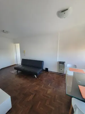 a room with a black couch on a wooden floor at departamento centro zona tribunales cordoba in Cordoba