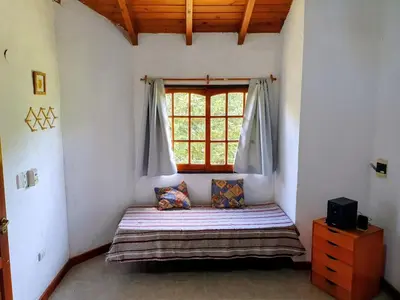 a bedroom with a bed in a room with a window at Cabañas Pioneras in Villa Rumipal