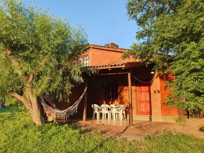 a house with tables and chairs on the porch at Cabañas Pioneras in Villa Rumipal