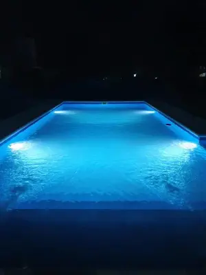 a blue swimming pool with lights in the dark at Cabañas Pioneras in Villa Rumipal