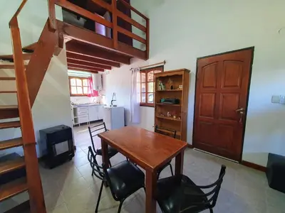 a dining room with a table and chairs and a staircase at Cabañas Pioneras in Villa Rumipal