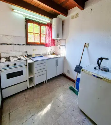 a kitchen with a white stove and a refrigerator at Cabañas Pioneras in Villa Rumipal