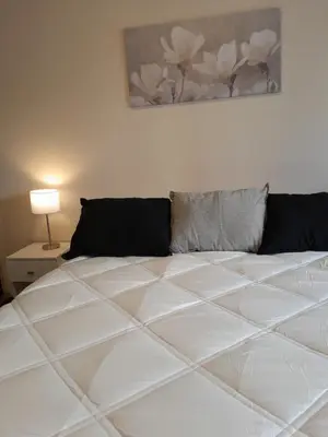 a bed in a bedroom with a white bedspread at Departamento Anita Villa Carlos Paz in Villa Carlos Paz