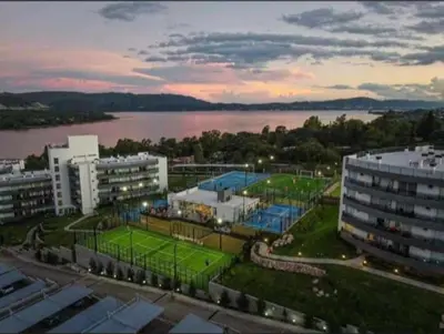 a large building with a tennis court in front of a lake at Veneto Village in Villa Parque Siquiman
