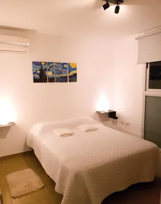 a white bedroom with a bed with two towels on it at Departamento céntrico con hermosa vista a las Sierras in Cordoba