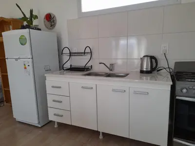 a white kitchen with a sink and a refrigerator at EL Mirador Soñado in Villa Carlos Paz
