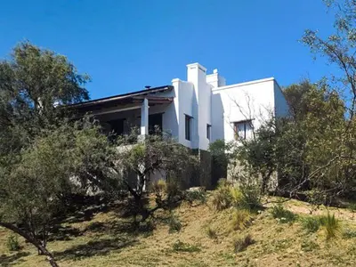 a white house on top of a hill with trees at Cabañas San Javier in Pueblito