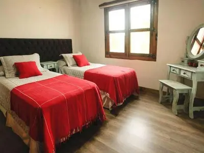 a bedroom with two beds with red sheets and a mirror at Cabañas San Javier in Pueblito