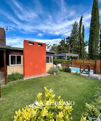 a house with an orange wall in a yard at El Bravo Alojamiento in Villa Rumipal