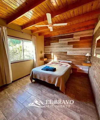 a bedroom with a bed and a wooden wall at El Bravo Alojamiento in Villa Rumipal