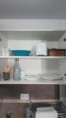 a kitchen counter with plates and a laptop on a shelf at Anicca Alberdi Córdoba Centro in Cordoba