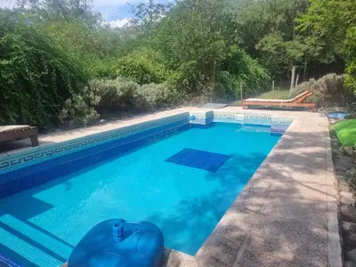 a swimming pool with blue water in a yard at Duplex Las Violetas in Merlo