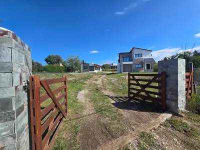 a wooden gate in a field next to a house at Gaviotas del Sur in Potrero de Garay