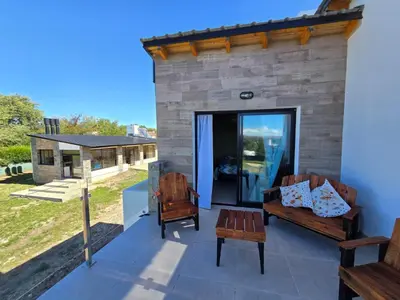 a patio with two chairs and a bench and a building at Gaviotas del Sur in Potrero de Garay