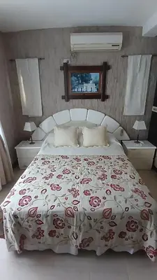 a bedroom with a large bed with a floral bedspread at CASA TODA EN PLANTA BAJA CON PARQUE y PILETA INDIVIDUAL SOBRE ASFALTO A POCAS CUADRAS DEL CENTRO DE MERLO in Merlo