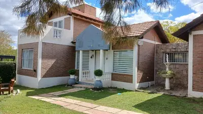 a brick house with a white door at CASA TODA EN PLANTA BAJA CON PARQUE y PILETA INDIVIDUAL SOBRE ASFALTO A POCAS CUADRAS DEL CENTRO DE MERLO in Merlo