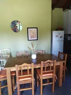 a dining room table with chairs and a refrigerator at Cabañas Tanti in Tanti