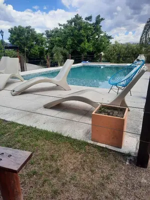 a group of white chairs sitting next to a swimming pool at Cabañas Tanti in Tanti