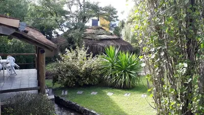 a garden with a thatched hut in the background at Cabañas Pedras Moras in Tanti