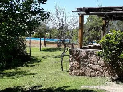 a garden with a stone wall and a pool at Cabañas Pedras Moras in Tanti
