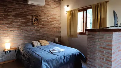 a bedroom with a blue bed in a brick wall at Las Acacias Suites in Las Rabonas