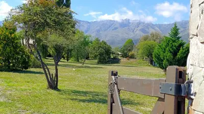 a fence with a tree and mountains in the background at Las Acacias Suites in Las Rabonas