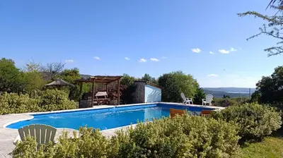 a swimming pool in a garden with chairs around it at Las Acacias Suites in Las Rabonas