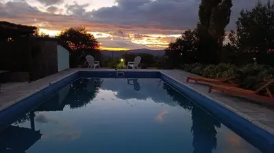 a swimming pool with a sunset in the background at Las Acacias Suites in Las Rabonas