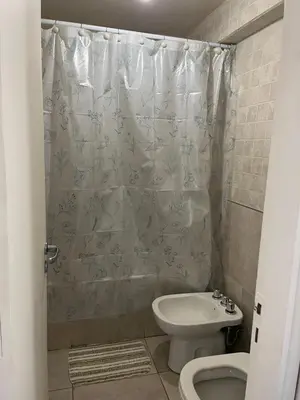 a bathroom with a shower curtain and a toilet and a sink at Dpto zona Clínica REINA FABIOLA con pileta in Cordoba