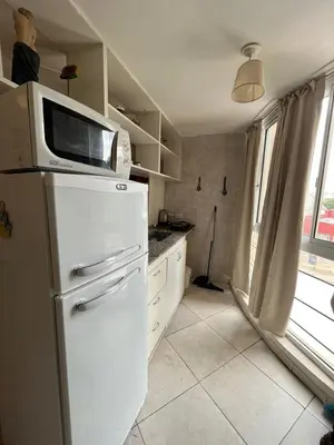 a kitchen with a microwave on top of a refrigerator at Dpto zona Clínica REINA FABIOLA con pileta in Cordoba