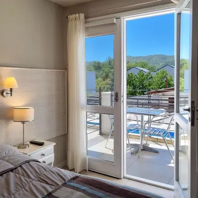 a bedroom with a bed and a balcony with a table at Tirol D'andrea in Villa General Belgrano