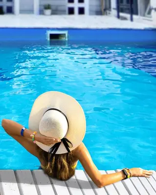 a woman in a hat sitting in a swimming pool at Tirol D'andrea in Villa General Belgrano