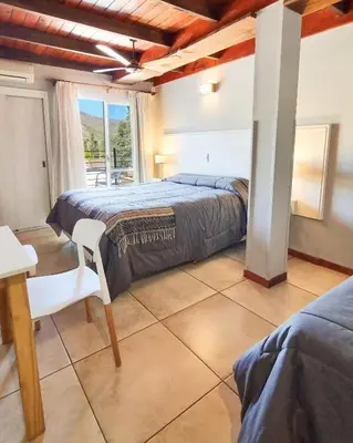 a bedroom with a bed and a table and a window at Tirol D'andrea in Villa General Belgrano