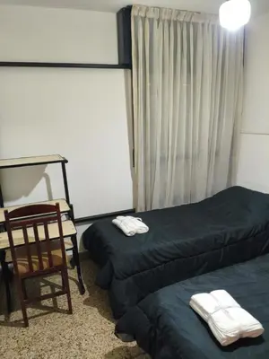 a room with two beds and a chair and a window at Departamento Barrio General Paz in Cordoba