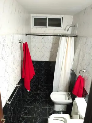a bathroom with a toilet and a sink with red towels at Departamento Barrio General Paz in Cordoba