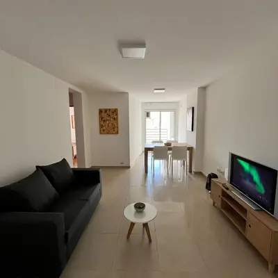 a living room with a black couch and a tv at Jardines del Boulevard 6 in Cordoba
