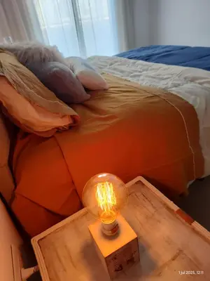 a lamp on a table in front of a bed at Espacio PAN in Villa Carlos Paz